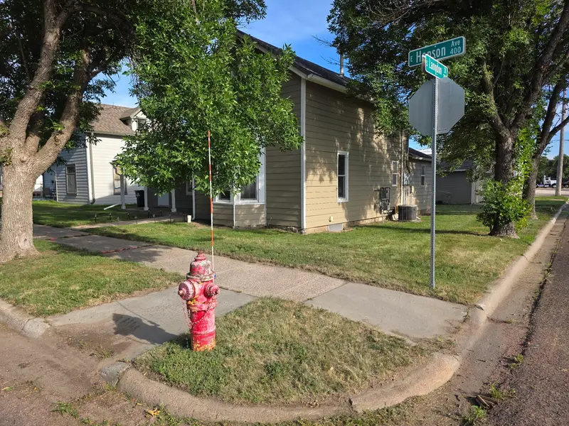 A mown corner lot with a red fire hydrant beside a tan house