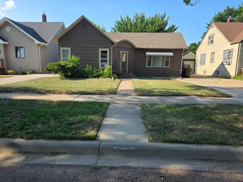 A mown front lawn and path in front of a grey single-storey home, seen from the street