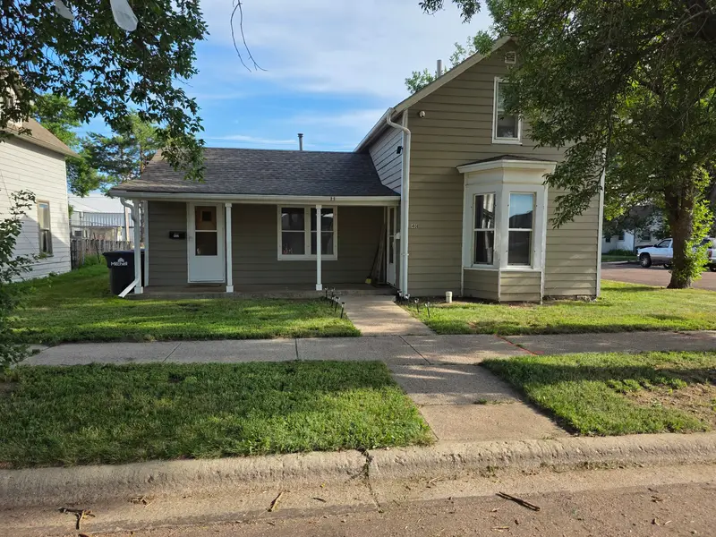 A mown front yard and walkway in front of a tan two-storey house